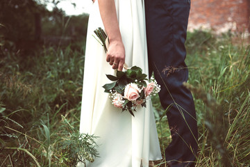 Bride holds a wedding bouquet in her hand with the groom
