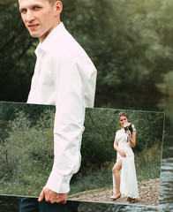 Groom holds a mirror in his hand which reflects the happy bride in heels