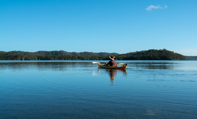 Man kayaking across a lake in Bungwahl, Australia
