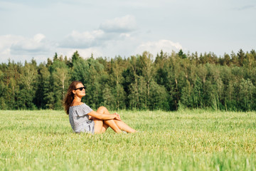 Woman wearing dress sitting on green grass field