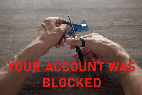 male hands with scissors cut the payment blue master card. concept of liquidation, destruction of deactivation, decommissioning with the inscription your account was blocked