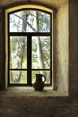 Still life with an old clay jug on the window in an abandoned house.