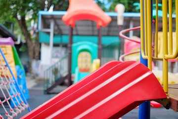 A closeup picture of a red slide at a playground in a public park.