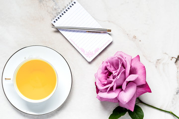 Rose Flower with cup of tea and note pad pen on Marble.   Relaxing Top View with Copy Space