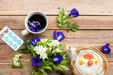 herbal healthy drinks blue water extract butterfly pea flowers and lozenge cough sore pills for health care with flowers arrangement flat lay style on background wooden