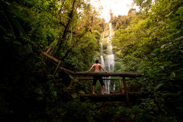 Hombre en puente de madera observando una cascada en medio de la naturaleza © FranciscoStockLife