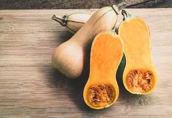 Butternut squash sliced ​​on a wooden table. Butternut is a bell-shape fruit with sweet...