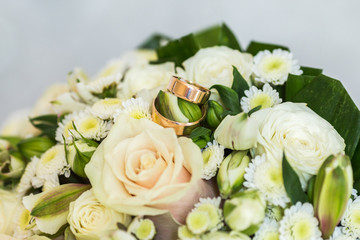 
Wedding rings on the background of a bouquet of roses close-up.