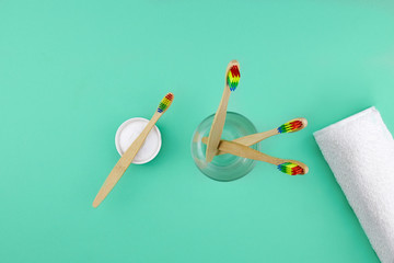 Bamboo toothbrushes, a white cotton towel and powder for brushing your teeth in bowl on  green backdrop.  No plastic, zero waste concept.