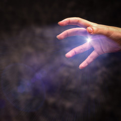 A hand with tense fingers sends a clot of energy against a dark background.