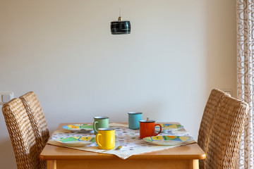 Fototapeta na wymiar Table setting with colorful mugs and plates for casual breakfast.