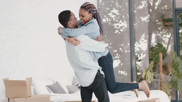 Young aAfrican couple have moved in a new apartment. The happy couple is hugging celebrating the moving day.
