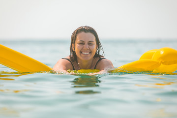 portrait of pretty smiling woman on yellow inflatable mattress
