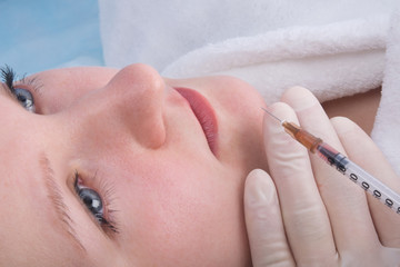 close-up, hands in sterile gloves, giving a beauty injection to a woman, in the chin