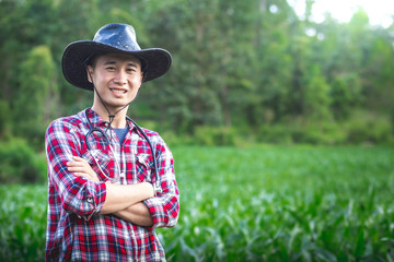 Young farmer standing and smiling in corn field, Agribusiness concept.