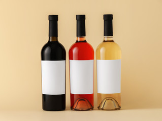 Bottles of wine with blank labels on color background. Mockup for design