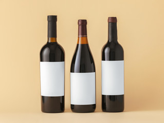 Bottles of wine with blank labels on color background. Mockup for design