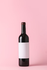Bottle of wine with blank label on color background. Mockup for design