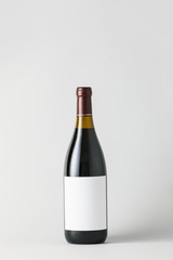 Bottle of wine with blank label on light background. Mockup for design