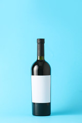 Bottle of wine with blank label on color background. Mockup for design