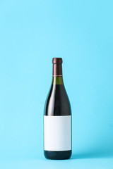 Bottle of wine with blank label on color background. Mockup for design
