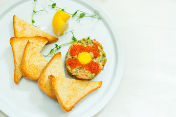 Breakfast on a white plate, top view with space. Sandwich with caviar and croutons