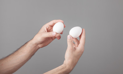 Male hands holding white chicken eggs.