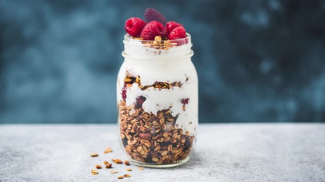 Healthy granola yogurt parfait with raspberries in a jar. Stop motion animation