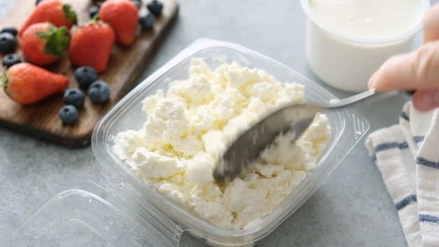 Cottage cheese or ricotta in plastic packaging on concrete table background. Healthy food for breakfast rich in Calcium and Protein