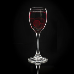 Homemade tincture of red cherry. Berry alcoholic drinks concept. Homemade red wine made from ripe cherries in wineglass on black background, Ukraine