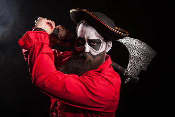 Man dressed up like a pirate for halloween holding and axe over black background.