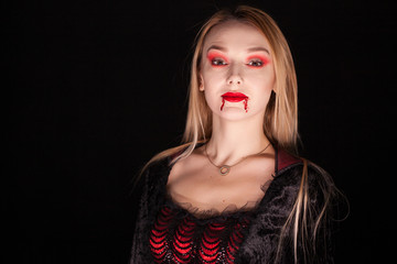 Beautiful vampire woman with dripping blood over black background.