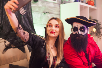 Cheerful pirate and vampire woman at halloween party taking a selfie.