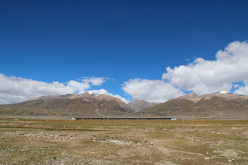 View of ice mountains and Qinghai–Tibet Railway track with the dramatic sky in Tibet, China