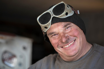 Portrait of a male worker in welding goggles with a dirty face. Auto Mechanic.