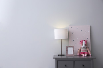Modern grey chest of drawers near light wall in child room, space for text. Interior design