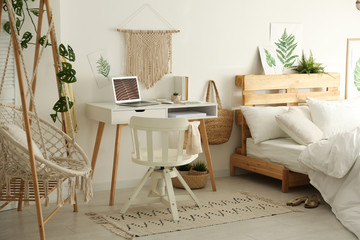 Stylish room interior with workplace, hanging chair and bed