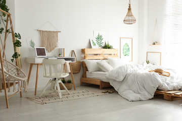 Stylish room interior with workplace, hanging chair and bed