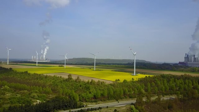 Aerial Pan: Windmill farm in field next to German electrical power plant