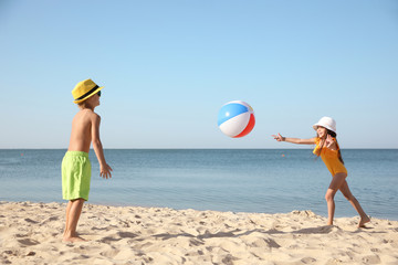 Cute little children playing with inflatable ball on sandy beach