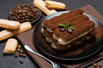 Classic tiramisu dessert and savoiardi cookies on ceramic plate on concrete background