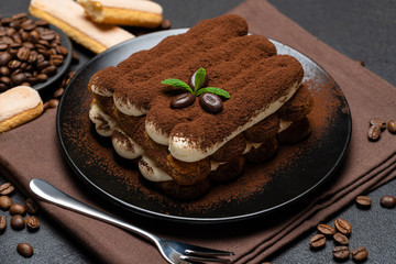 Classic tiramisu dessert and savoiardi cookies on ceramic plate on concrete background