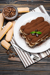 Classic tiramisu dessert on ceramic plate on wooden background
