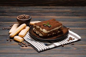 Classic tiramisu dessert on ceramic plate on wooden background