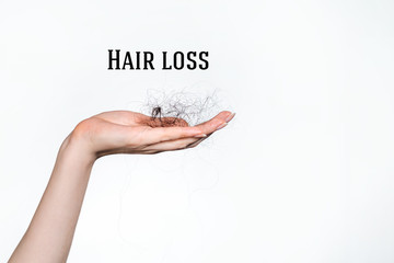 Hair loss. A female hand holds a bunch of fallen hair. Copy space. White background. Concept of alopecia and hair care