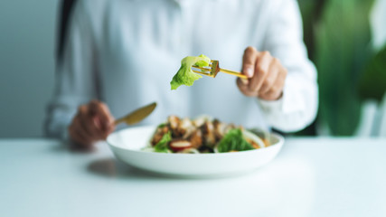 Closeup image of a woman eating chicken salad on table in the restaurant