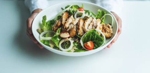 Closeup image of a woman holding a plate of chicken salad