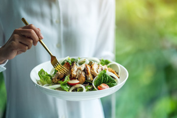 Closeup image of a woman holding and eating chicken salad