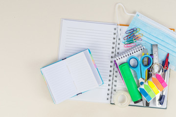 Shopping cart with school supplies, protective mask, alcohol gel. Back to school during a covid-19 pandemic.