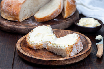 Two piece of Classic Boule bread with butter on  wooden plate, horizontal